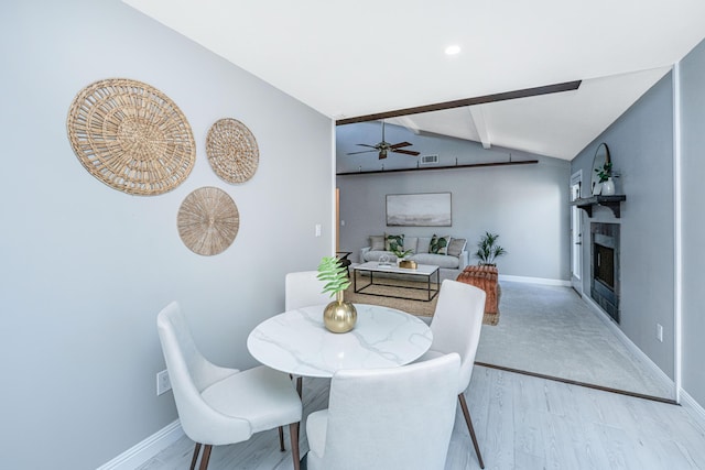 dining area featuring lofted ceiling with beams, baseboards, wood finished floors, and a fireplace