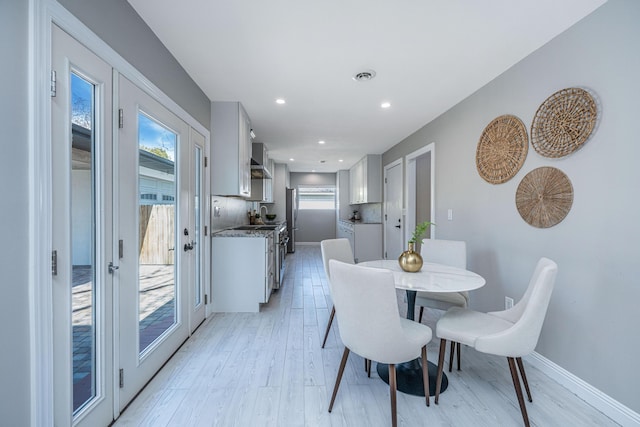 dining area featuring baseboards, a healthy amount of sunlight, and light wood finished floors