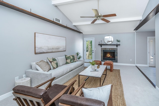 carpeted living area with visible vents, a tile fireplace, vaulted ceiling with beams, and baseboards