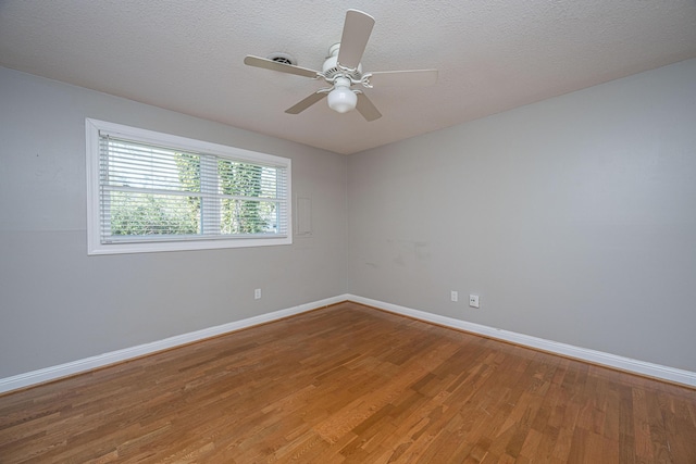 empty room with a textured ceiling, light wood-type flooring, and baseboards