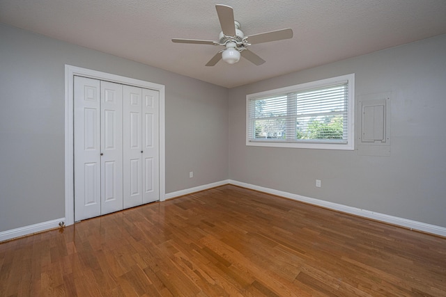 unfurnished bedroom featuring ceiling fan, baseboards, wood finished floors, a closet, and a textured ceiling