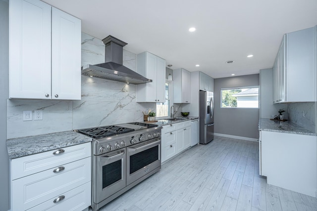 kitchen featuring a sink, wall chimney range hood, tasteful backsplash, and stainless steel appliances