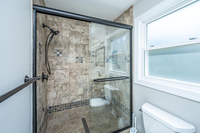 full bathroom with toilet, a shower stall, and a textured ceiling