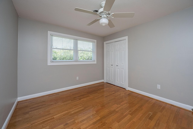 unfurnished bedroom featuring light wood-style flooring, a ceiling fan, baseboards, and a closet