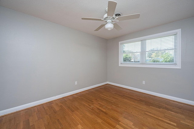 spare room featuring light wood-style flooring, a ceiling fan, and baseboards