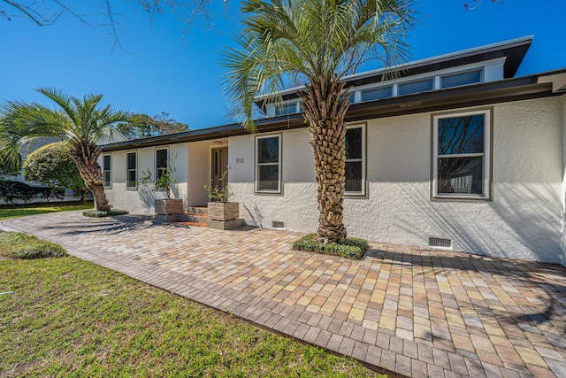 back of property with crawl space, stucco siding, and a patio