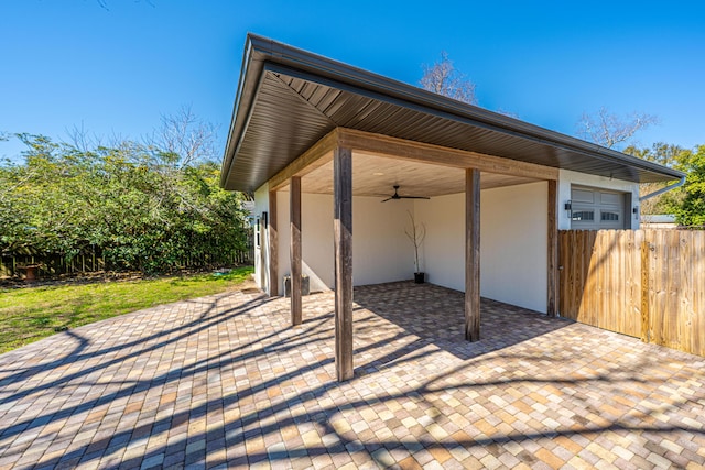 view of patio / terrace with a garage, ceiling fan, and fence