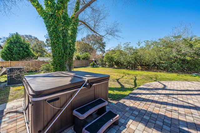 view of patio featuring central air condition unit, a fenced backyard, and a hot tub