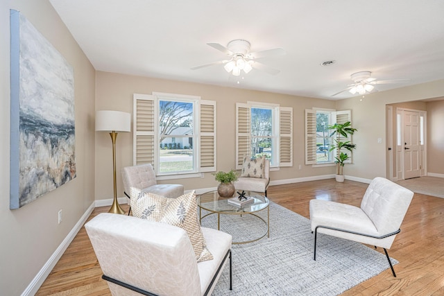 living room featuring light wood finished floors, a ceiling fan, and baseboards