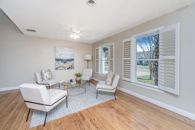 sitting room with baseboards, a ceiling fan, visible vents, and light wood-type flooring