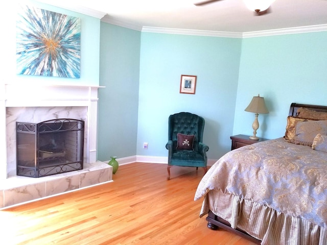 bedroom with wood-type flooring, ornamental molding, and a high end fireplace