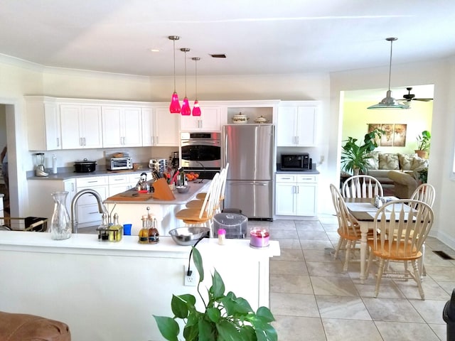 kitchen with pendant lighting, light tile patterned flooring, white cabinets, and appliances with stainless steel finishes