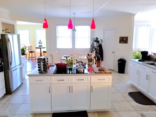 kitchen featuring light tile patterned flooring, stainless steel refrigerator, hanging light fixtures, and white cabinets