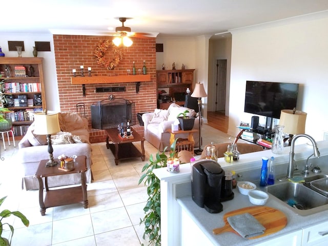 living room featuring ornamental molding, sink, ceiling fan, light tile patterned flooring, and a brick fireplace