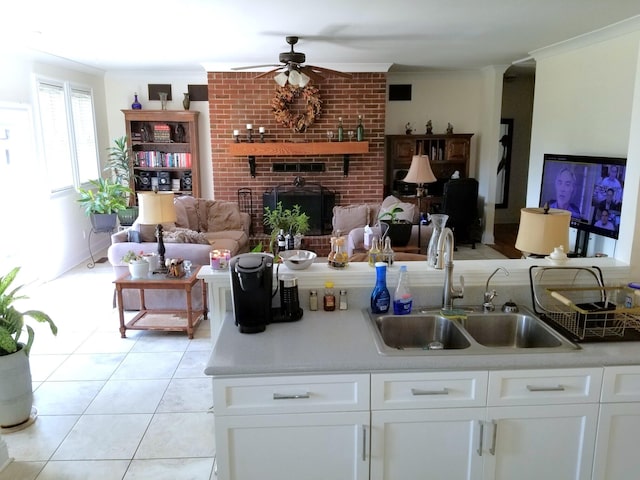 kitchen featuring ceiling fan, white cabinets, a brick fireplace, and sink