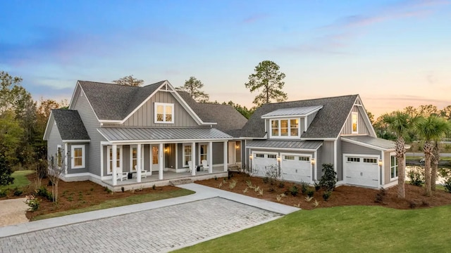 view of front of home featuring covered porch, a garage, and a yard