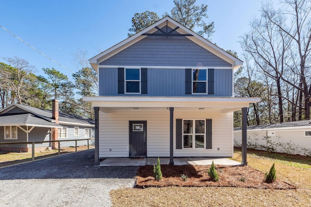 view of front of home featuring gravel driveway, a porch, and board and batten siding