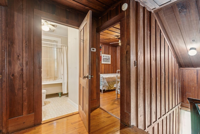 hallway with wood ceiling, wooden walls, and light hardwood / wood-style flooring