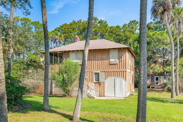 back of house featuring a yard and a storage shed