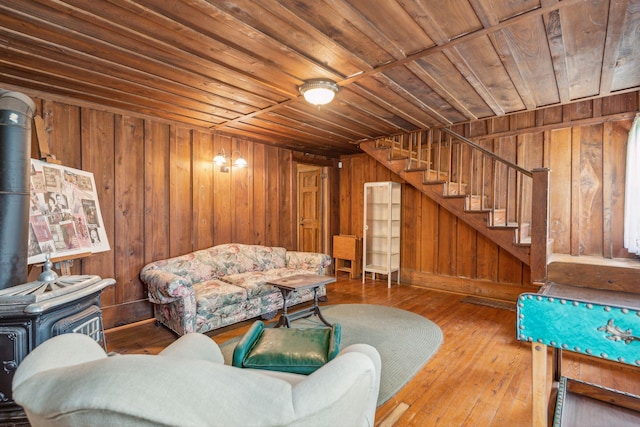 living room with wood walls, wooden ceiling, wood-type flooring, and a wood stove