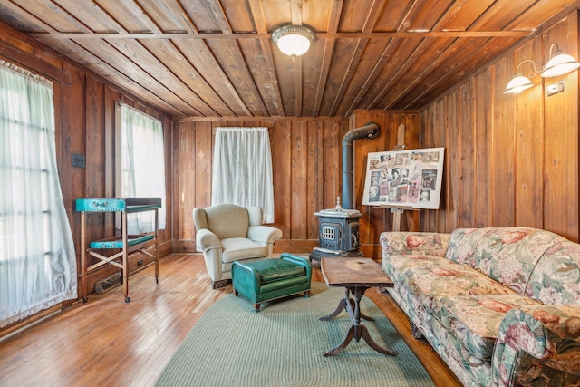 living area featuring a wood stove, hardwood / wood-style floors, wooden ceiling, and wood walls