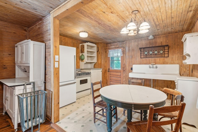 dining room with a notable chandelier, sink, wooden ceiling, and wood walls