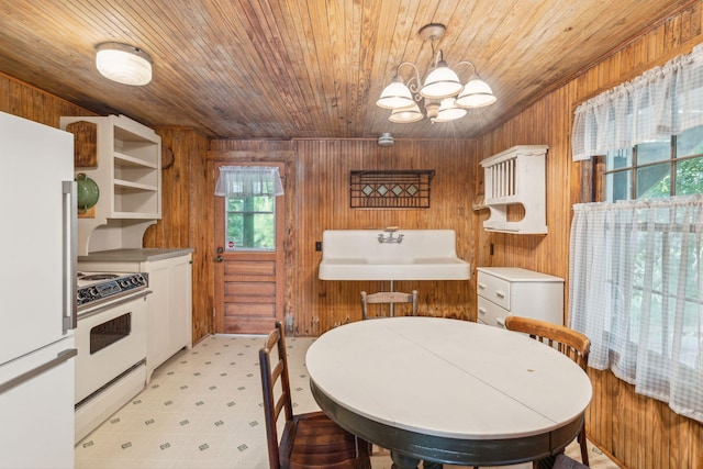 dining area with wood ceiling, wooden walls, a chandelier, and sink