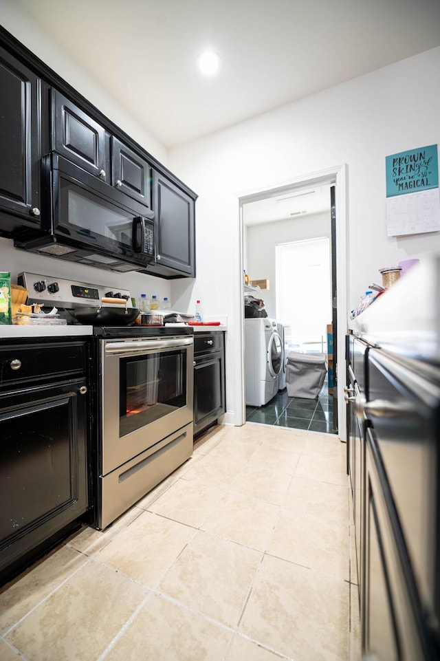 kitchen featuring light tile patterned floors, washer and dryer, and stainless steel electric range oven