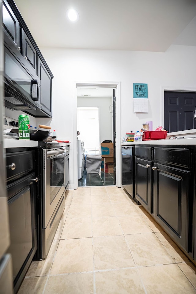 kitchen with stainless steel electric range oven, washing machine and dryer, light tile patterned floors, and beverage cooler