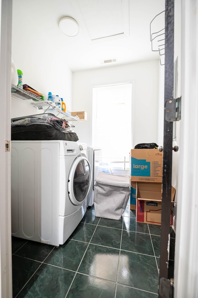 clothes washing area with dark tile patterned flooring and independent washer and dryer