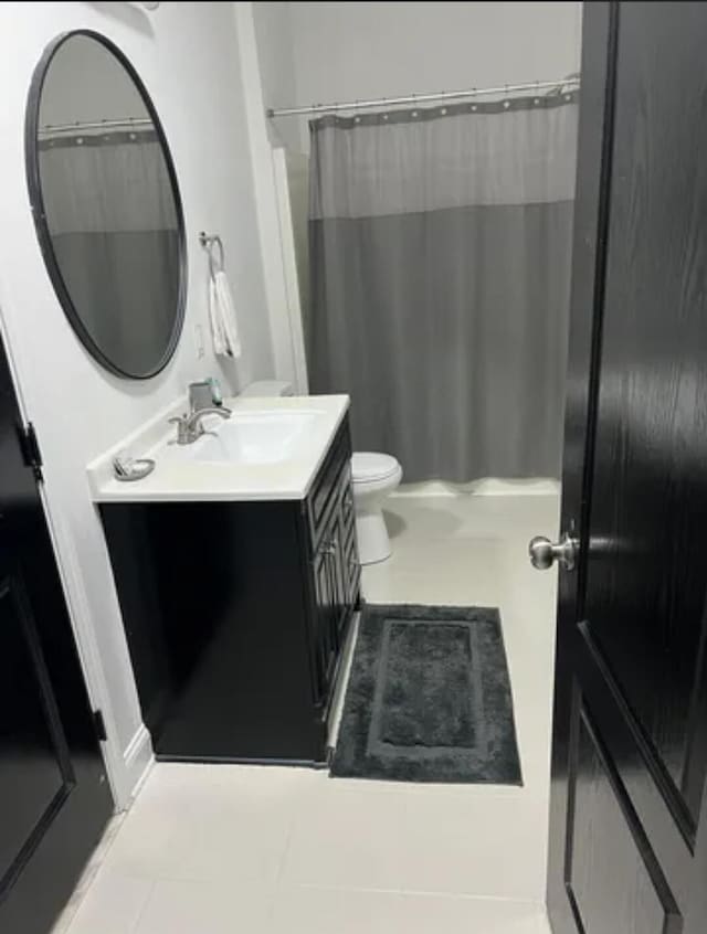 bathroom featuring vanity, tile patterned floors, toilet, and walk in shower