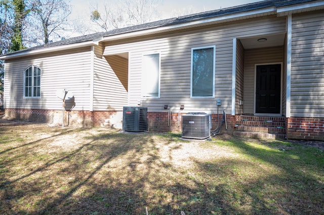 rear view of property featuring cooling unit and a yard