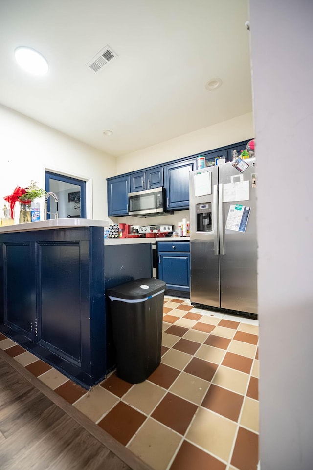 kitchen with stainless steel appliances, sink, and blue cabinets