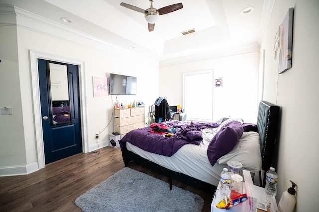 bedroom with a tray ceiling, dark hardwood / wood-style floors, and ceiling fan