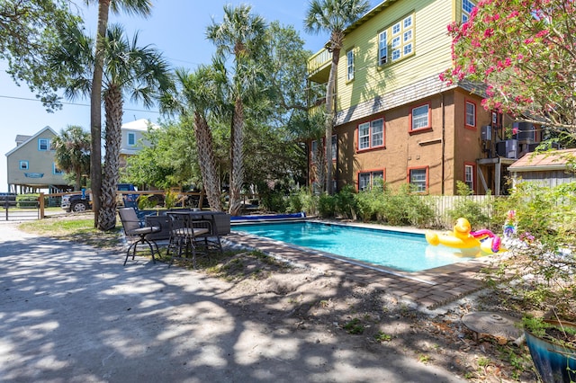 pool with a patio, fence, and cooling unit
