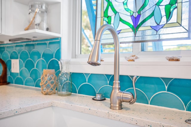 details featuring a sink, light stone countertops, and tasteful backsplash