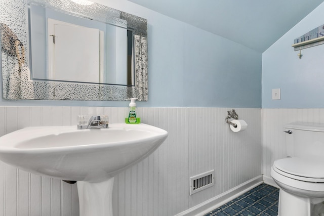 bathroom with toilet, visible vents, wainscoting, and a sink