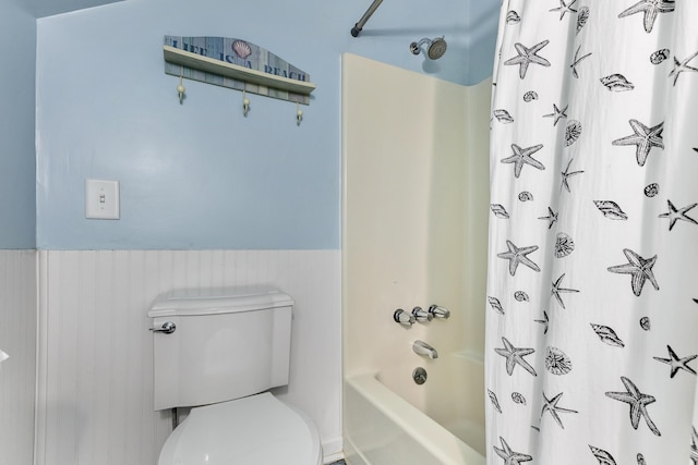 full bathroom featuring toilet, shower / tub combo, and a wainscoted wall
