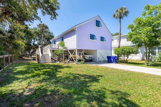 back of property with stairs, a yard, driveway, and a carport