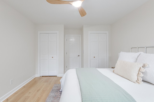 bedroom featuring ceiling fan, light hardwood / wood-style flooring, and two closets