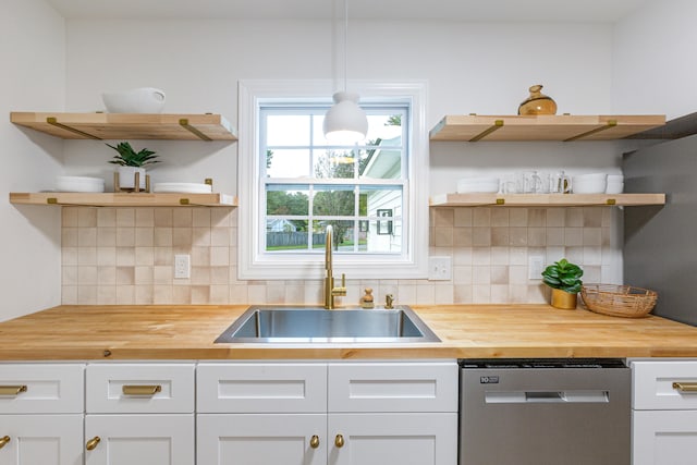 kitchen with sink, butcher block countertops, stainless steel dishwasher, pendant lighting, and white cabinetry