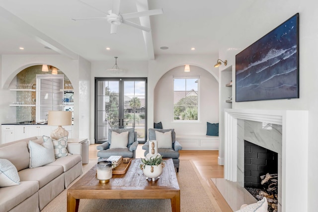 living room with ceiling fan, light wood-type flooring, a high end fireplace, and french doors