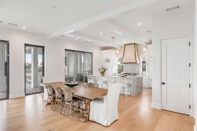 dining space featuring beamed ceiling and light wood-type flooring