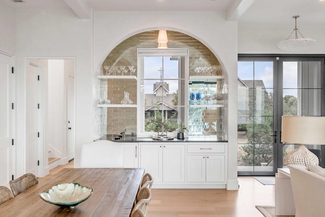 bar featuring beamed ceiling, light hardwood / wood-style flooring, white cabinets, and decorative light fixtures