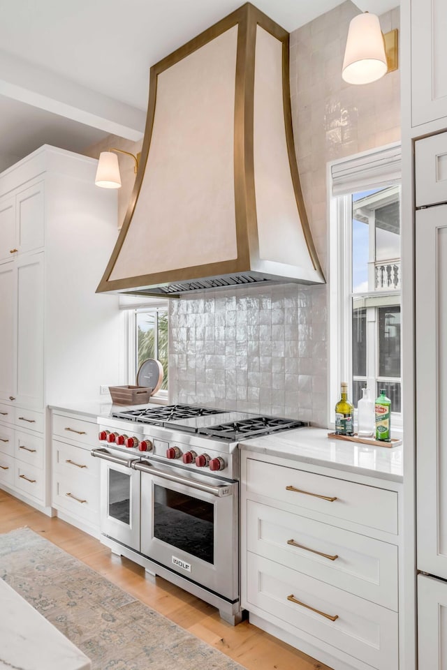 kitchen with plenty of natural light, custom range hood, light hardwood / wood-style floors, and range with two ovens