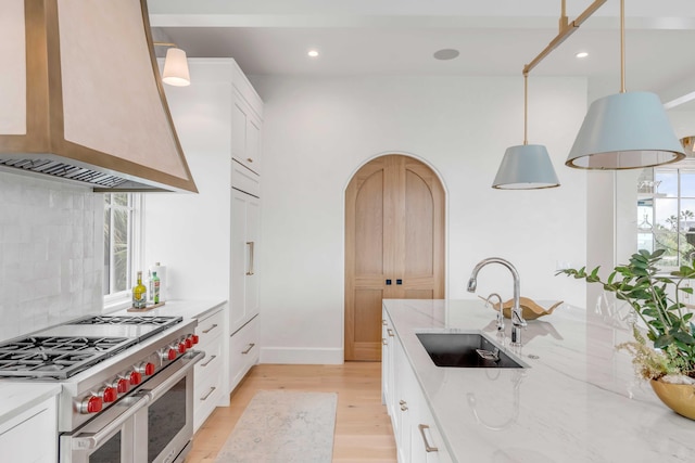 kitchen with white cabinets, wall chimney exhaust hood, and premium stove