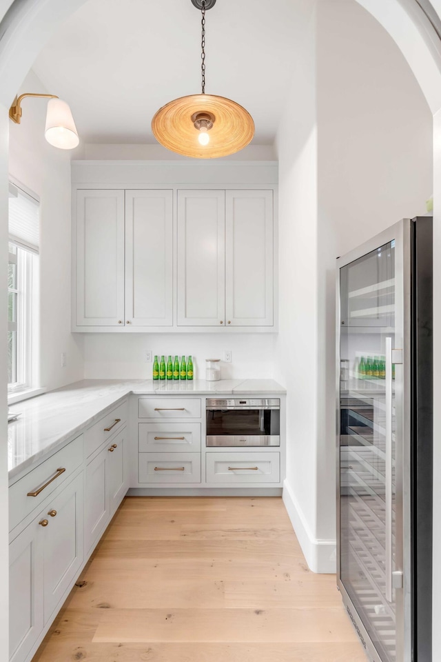 kitchen featuring white cabinetry, pendant lighting, and beverage cooler