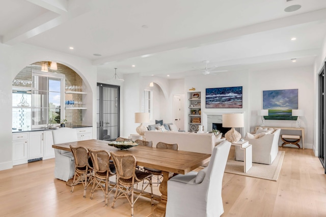 dining room with ceiling fan, beam ceiling, and light hardwood / wood-style flooring