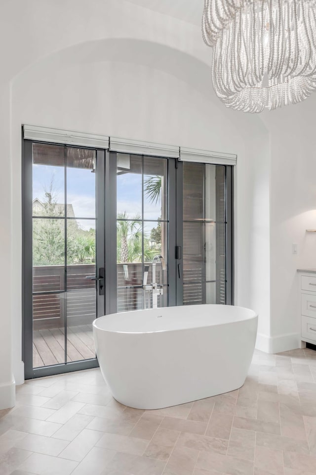 bathroom with tile patterned flooring, a washtub, vanity, and a notable chandelier