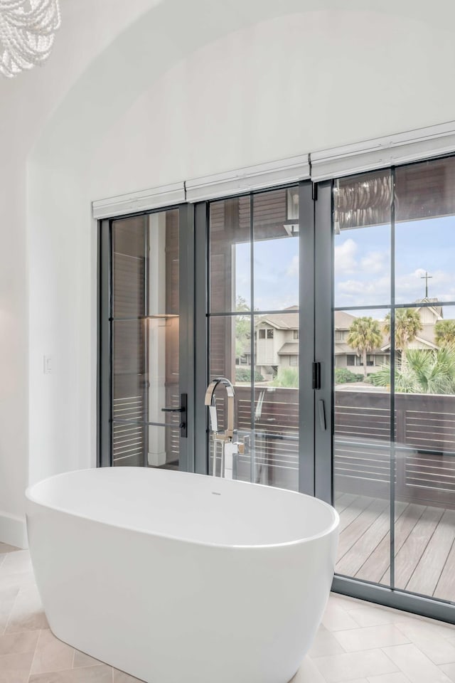 bathroom with tile patterned flooring, a bathtub, and a notable chandelier